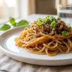 Honey sesame shirataki noodles glazed in warm sauce on white plate