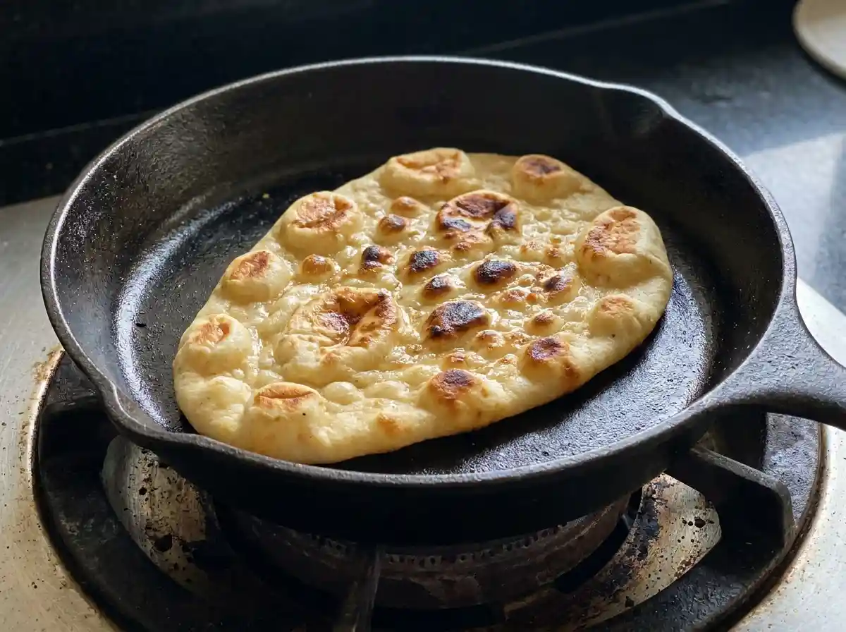 Naan_bread_cooking_in_skillet_202609061256 Cooking honey ginger naan recipe in a hot skillet